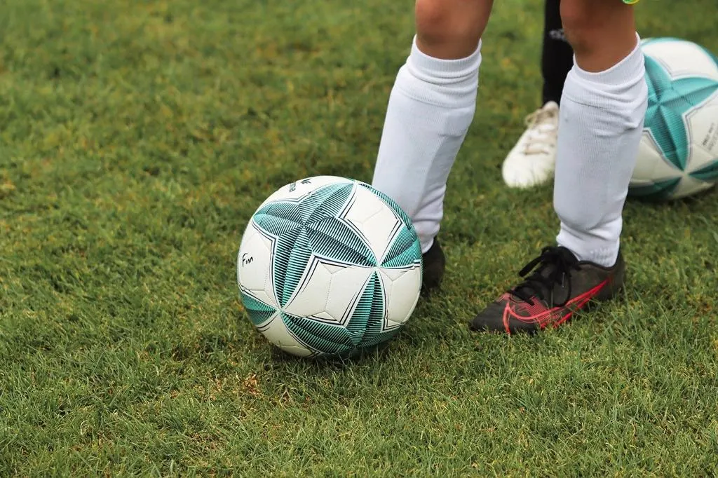 Kinderfüße am Ball auf dem Trainingsplatz